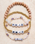 Set of beaded bracelets with 'WWJD' charms on a beige background