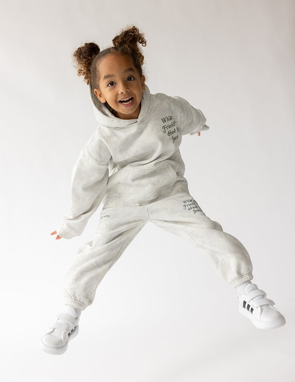 Child jumping in the What a Friend in Jesus white camo hoodie with coordinating pants