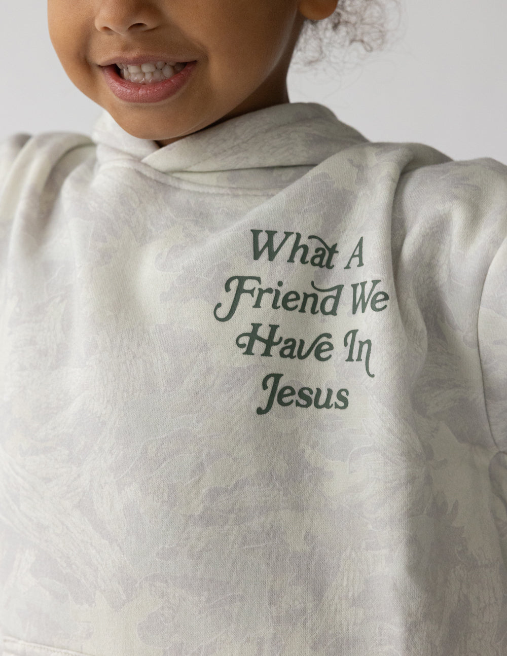 Close-up of green What a Friend We Have in Jesus chest lettering on the white camo kids hoodie