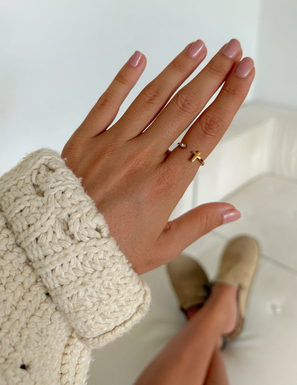 Wrapped Cross Gem gold-tone ring worn on a hand with a cream knit sleeve indoors