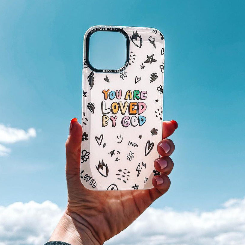 Phone case with 'You are loved by God' text held against a blue sky