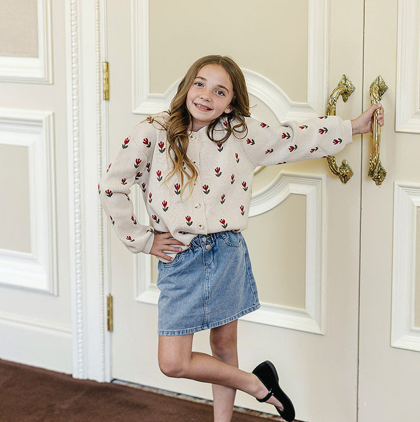 Young girl standing in a room with decorative doors and a brown rug.
