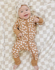 Baby in a floral onesie lying on a checkered blanket
