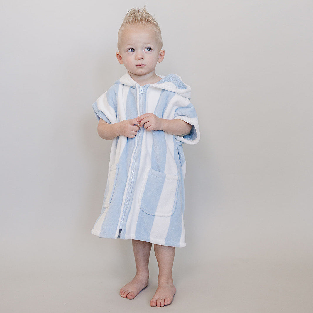 Child wearing a blue and white striped towel on a plain background