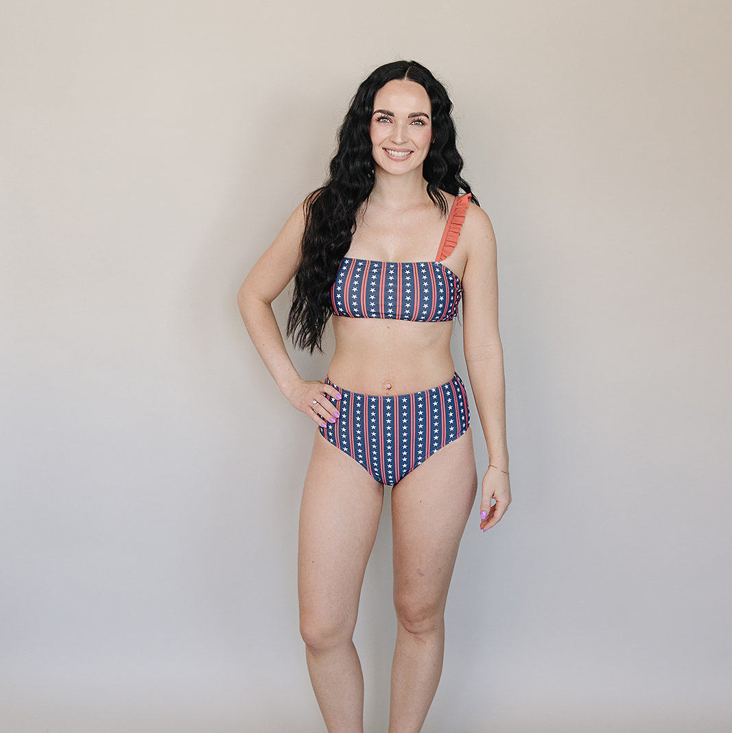 Woman wearing a patterned bikini standing against a plain background