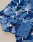 Blue camouflage long-sleeve shirt with lightning bolt pattern on a beige background