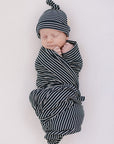Newborn baby swaddled in black and white stripes on a light background