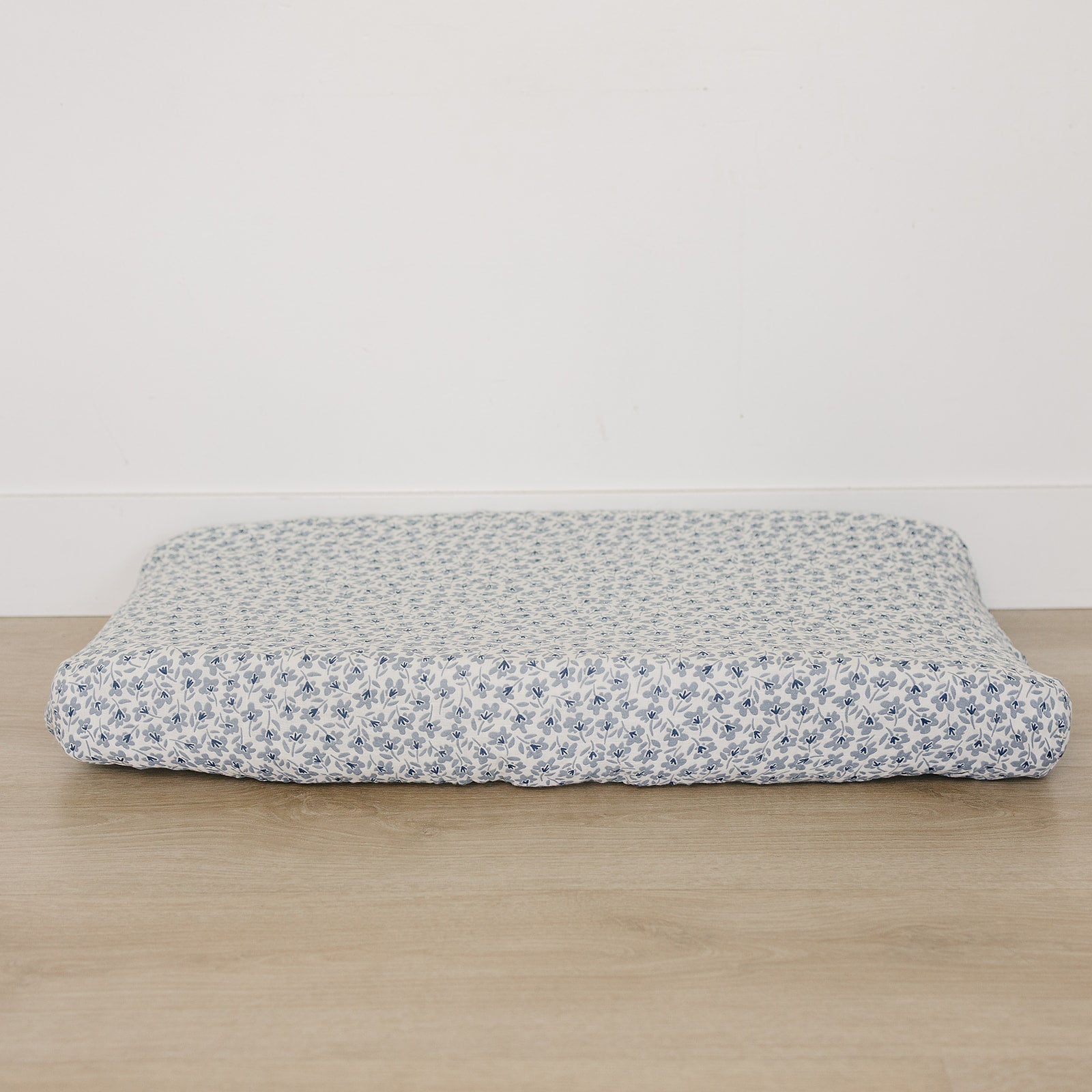 Floral-patterned mattress cover on a wooden surface with a white background