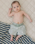 Baby lying on a quilted surface with a striped blanket