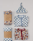 Collection of baby clothing and accessories including a floral blanket, checkered hat, and patterned outfit on a gray background.