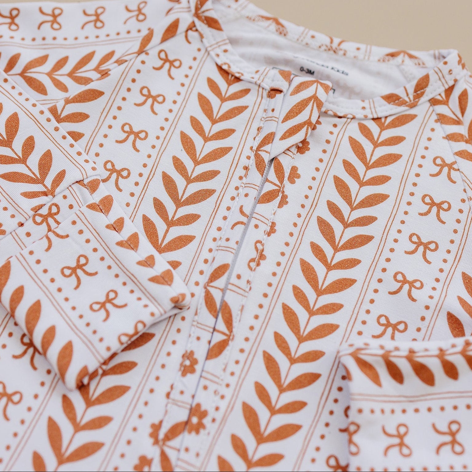 Folded fabric with orange leaf pattern on a beige background