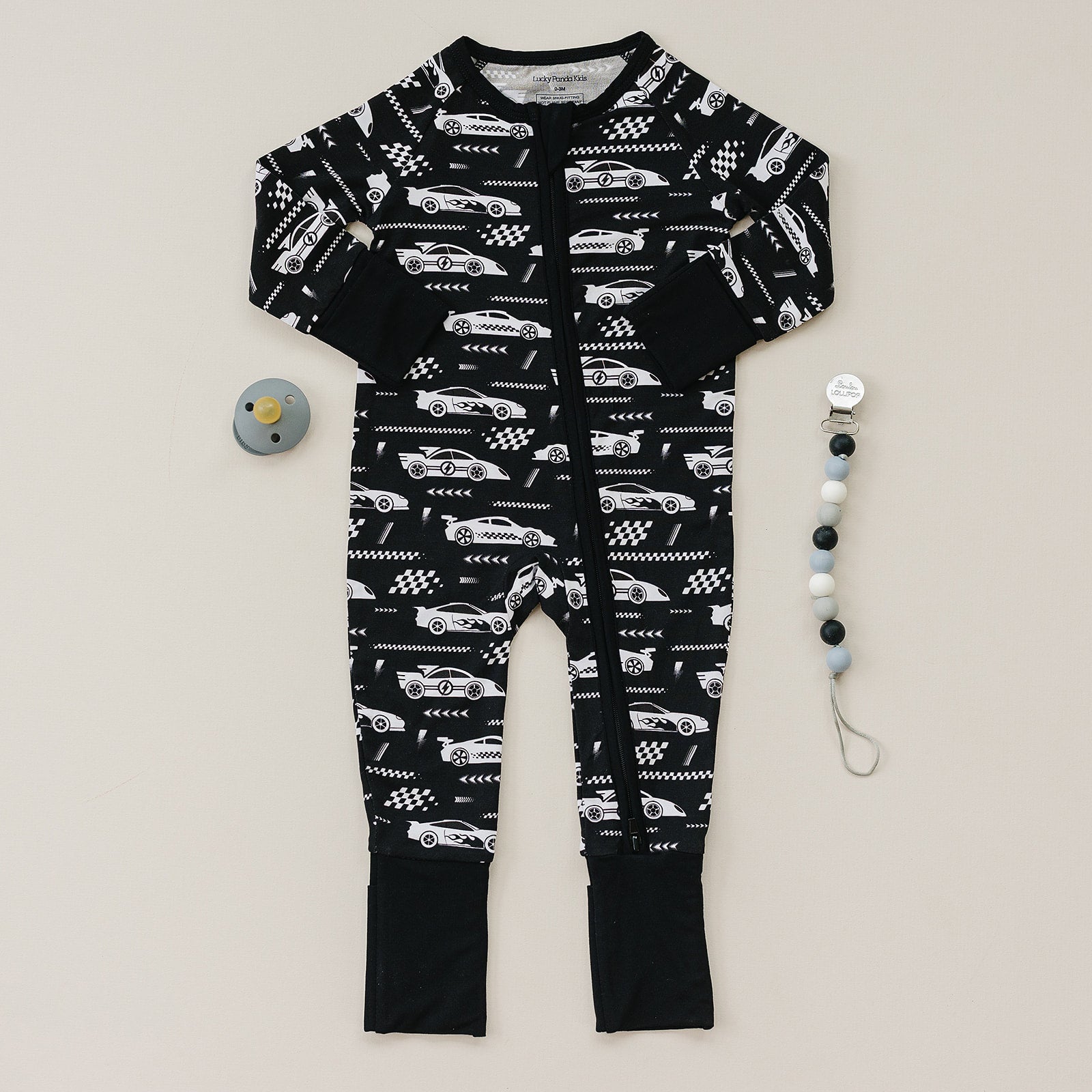 Black baby onesie with car pattern and two安抚teethers on a light gray background