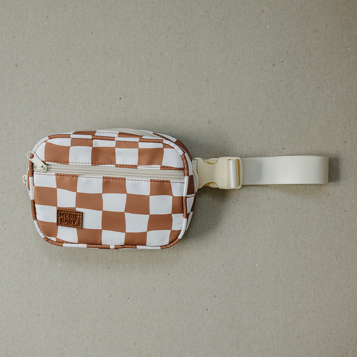 Checkered pattern waist bag with a strap on a beige background
