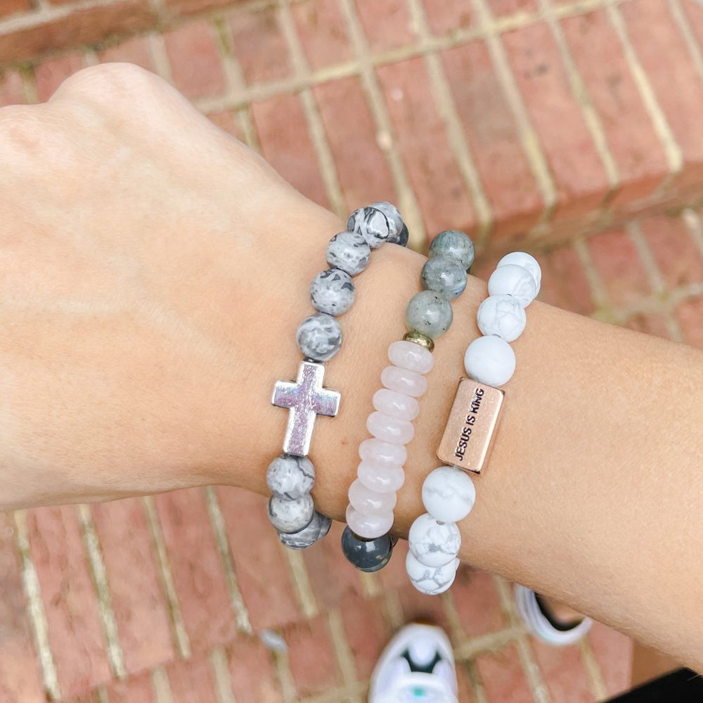 Three bracelets on a wrist with a brick background