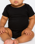 Infant wearing the BELLA + CANVAS 134B black triblend one piece, seated front view, ideal for custom printing