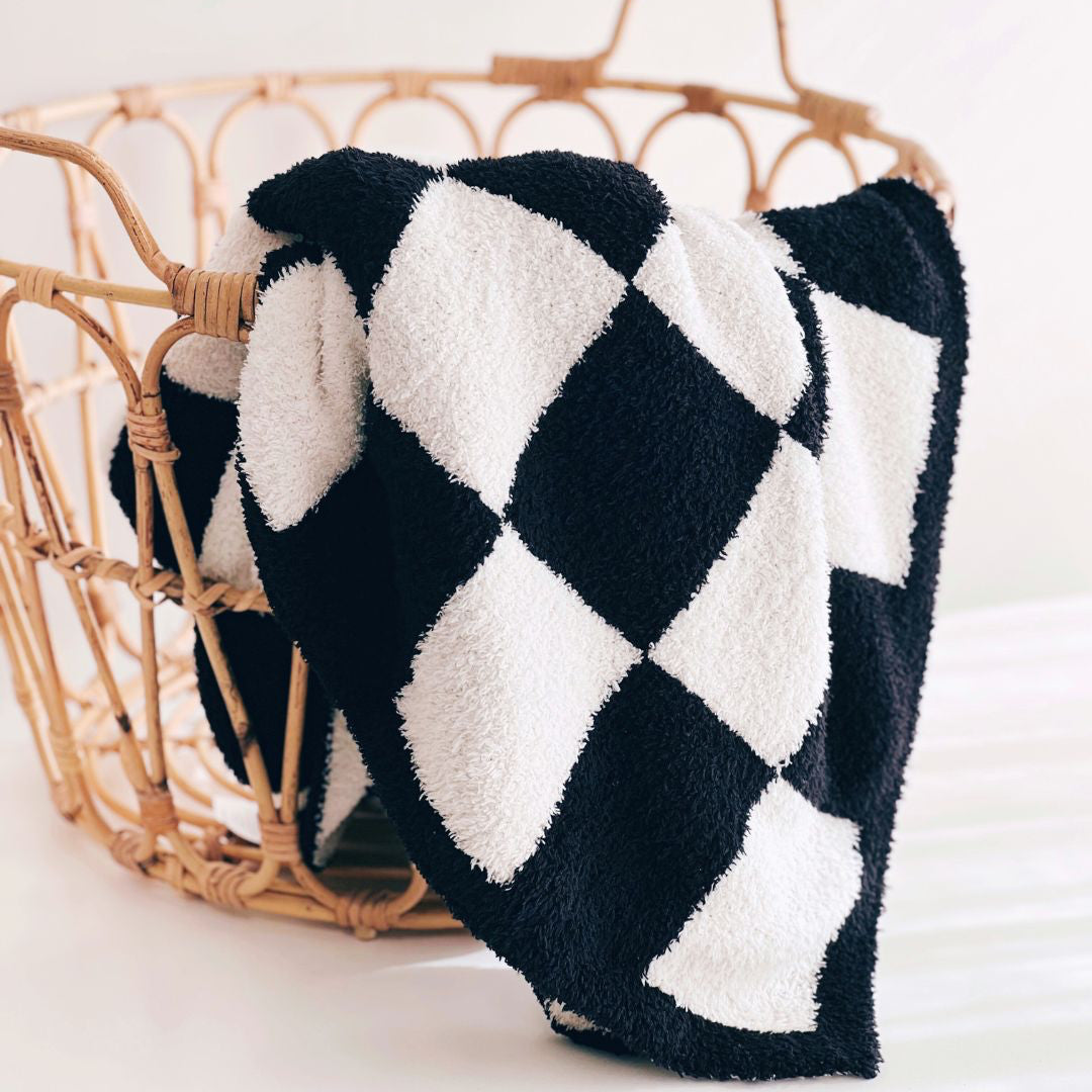Black and white checkered blanket in a wicker basket on a light background