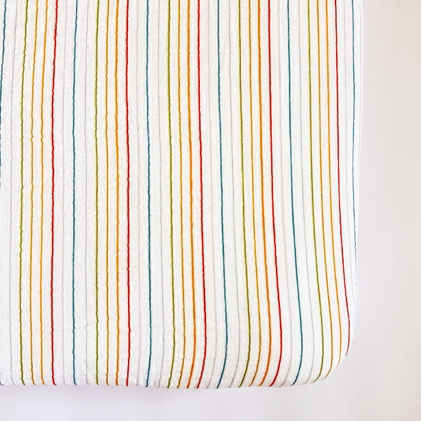Fitted crib sheet with multicolored stripes on a white background