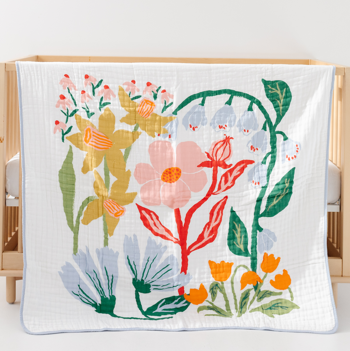 Floral-patterned blanket on a wooden crib with a white background