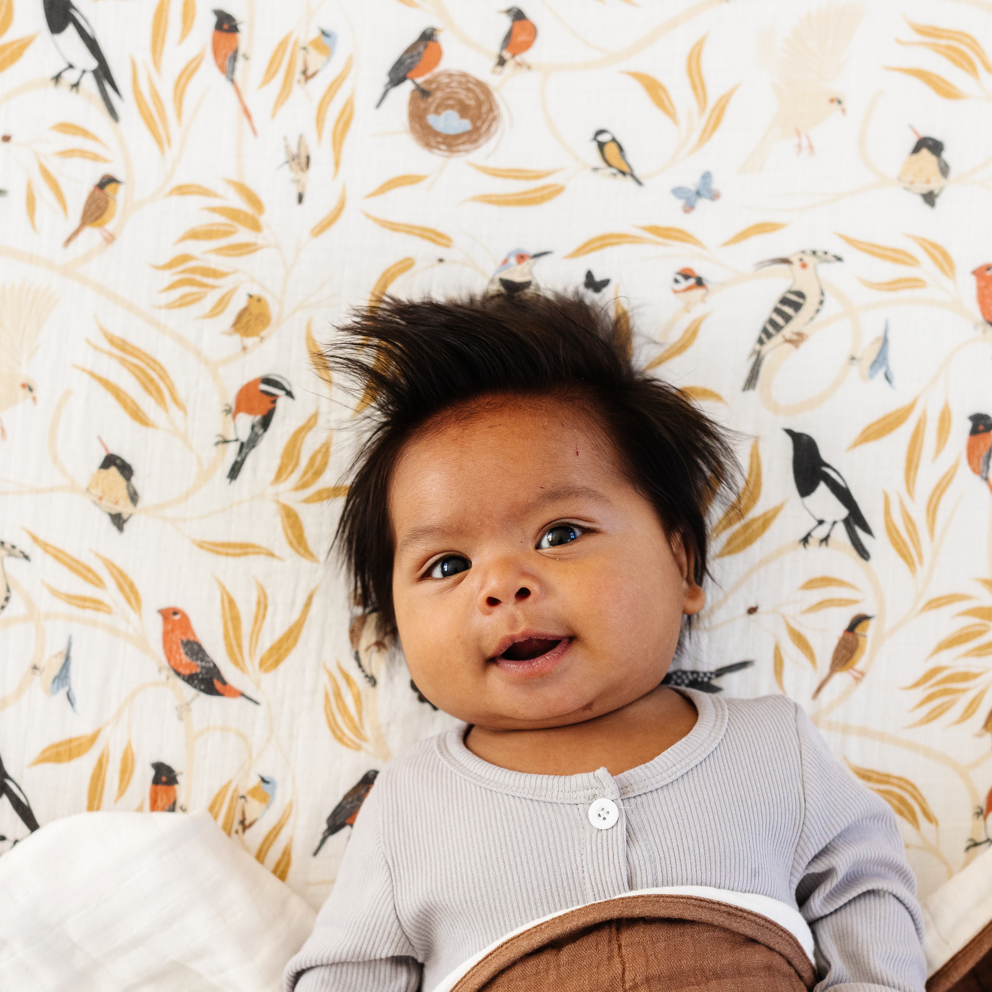 Baby lying on a bed with a patterned wall in the background