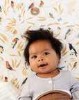 Baby lying on a bed with a patterned wall in the background