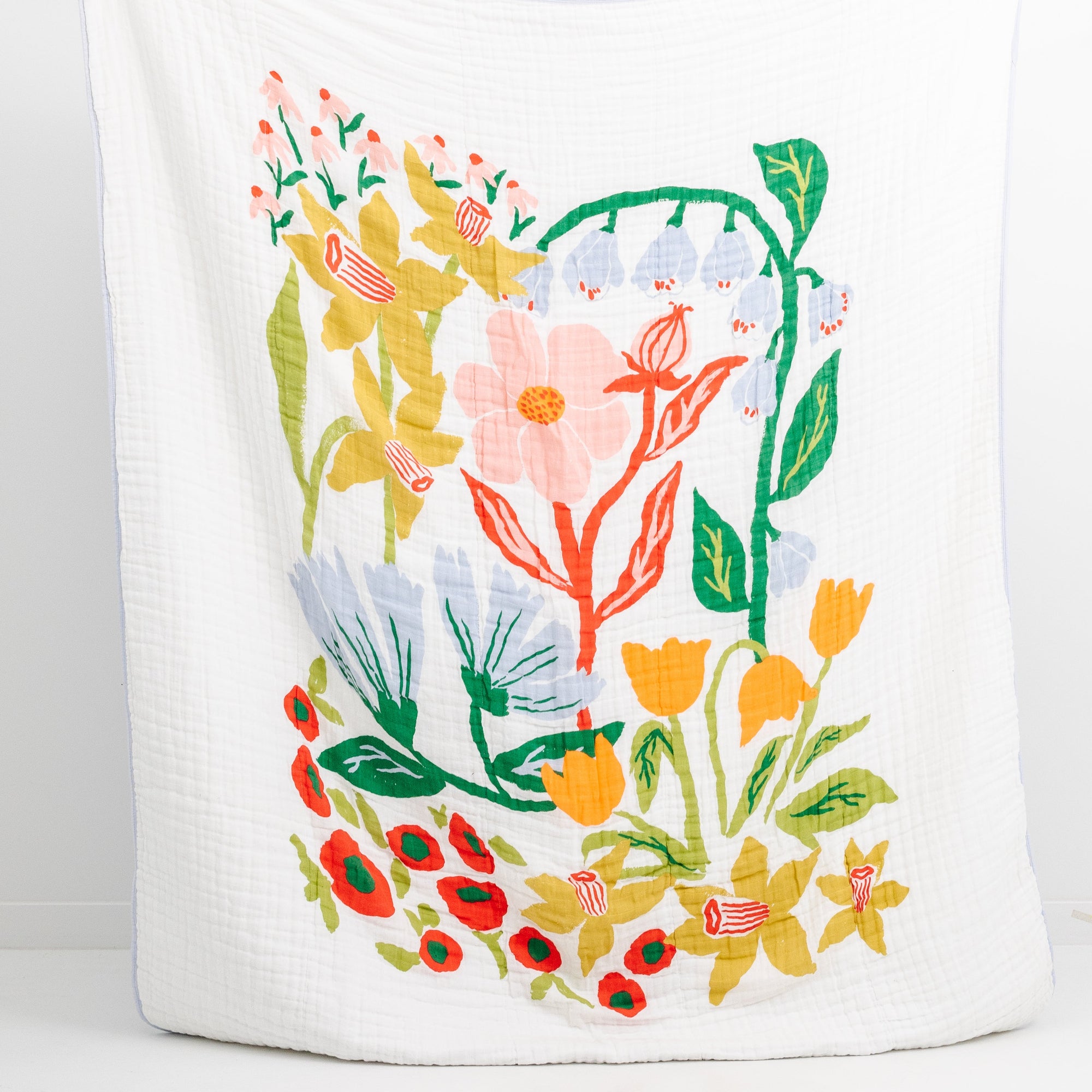 Person holding a large white pillow with colorful floral design on a white background