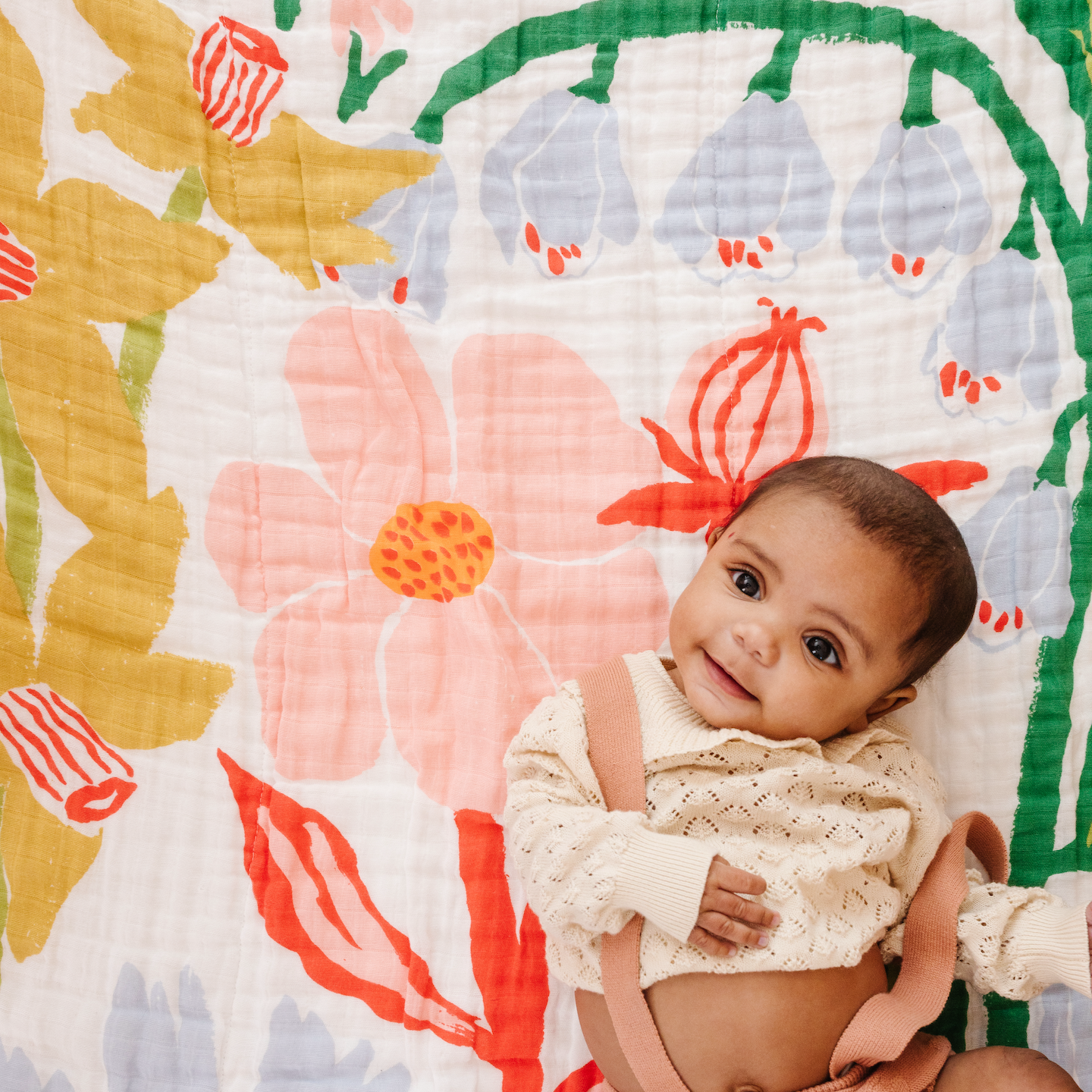 Baby sitting on a colorful floral-patterned blanket