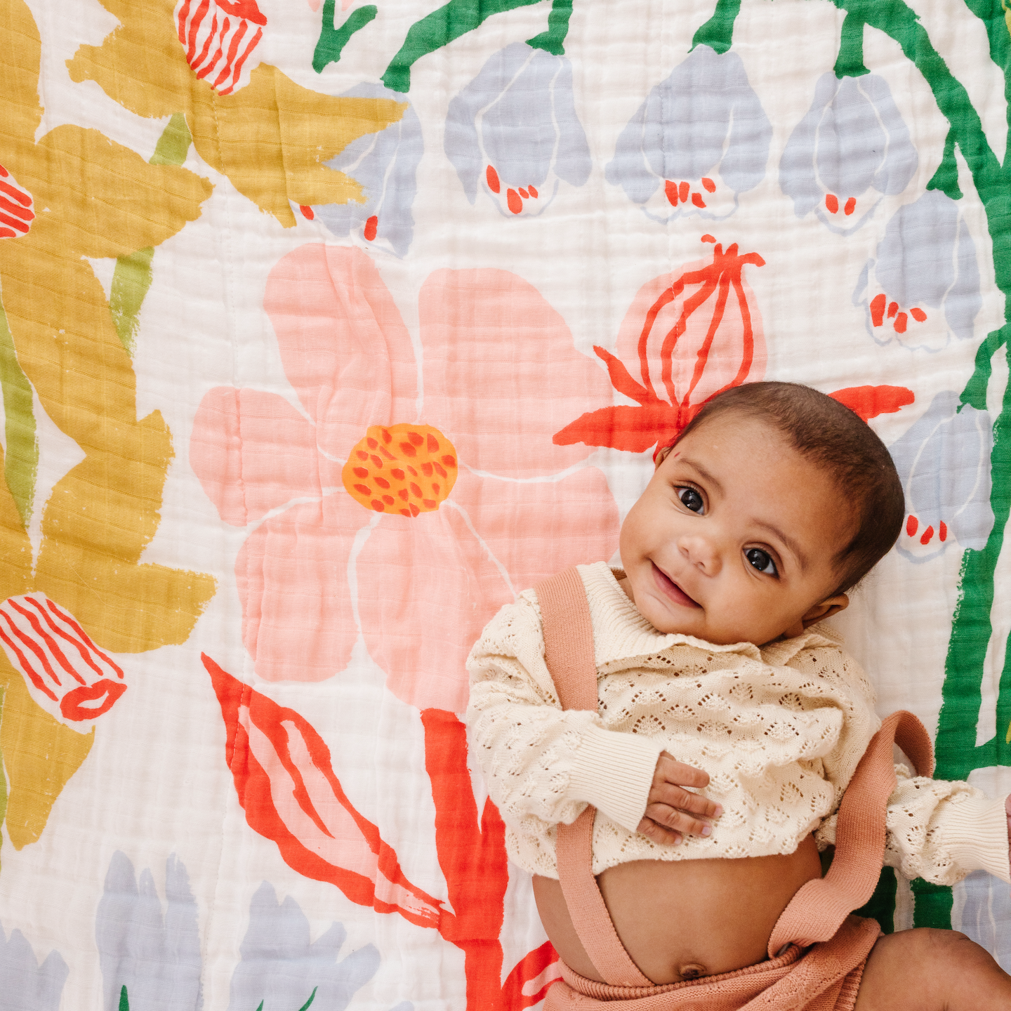 Baby sitting on a colorful floral-patterned blanket