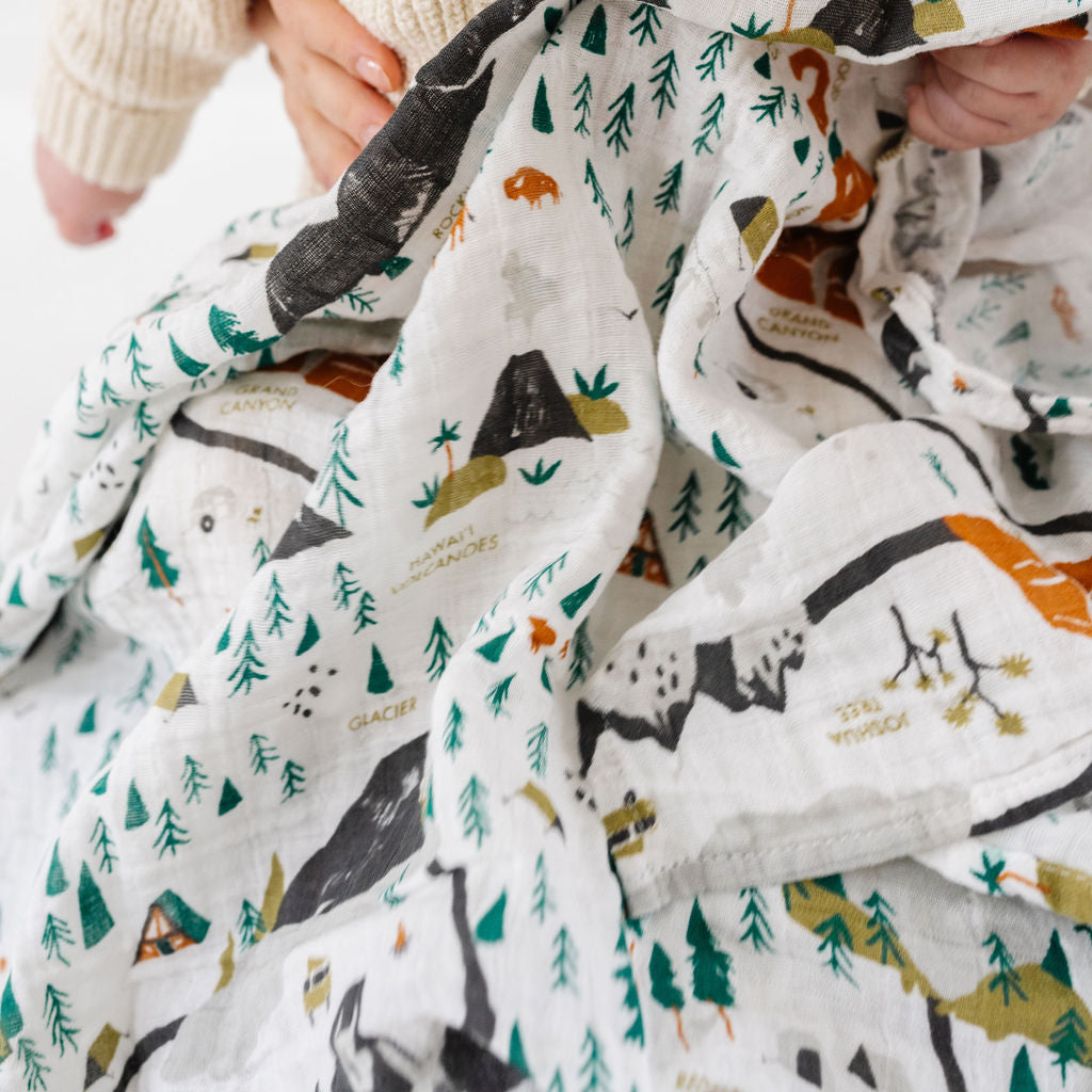 Baby holding a blanket with animal patterns on a white background