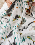 Baby holding a blanket with animal patterns on a white background