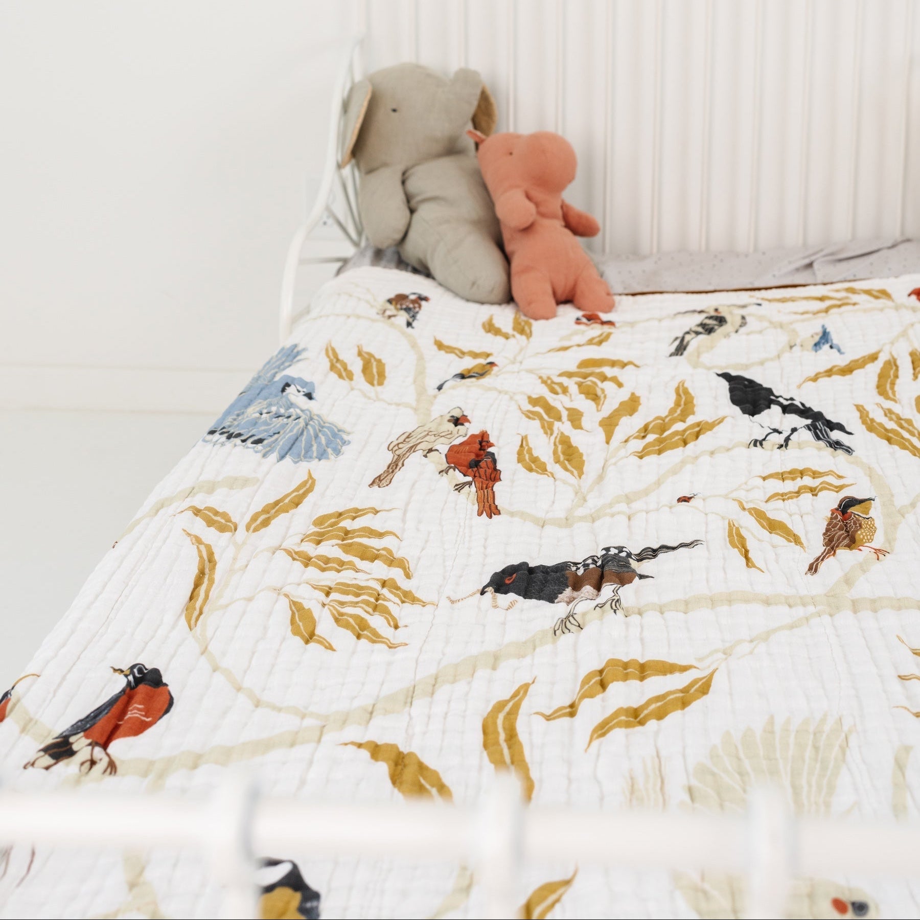 Children's room with a bed featuring animal-patterned bedding and stuffed toys.