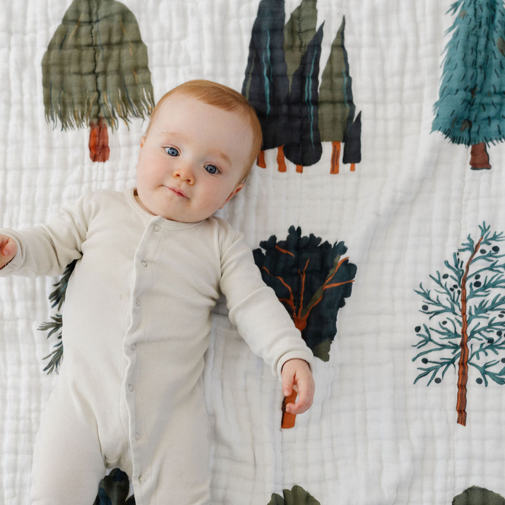 Baby lying on a quilt with tree pattern