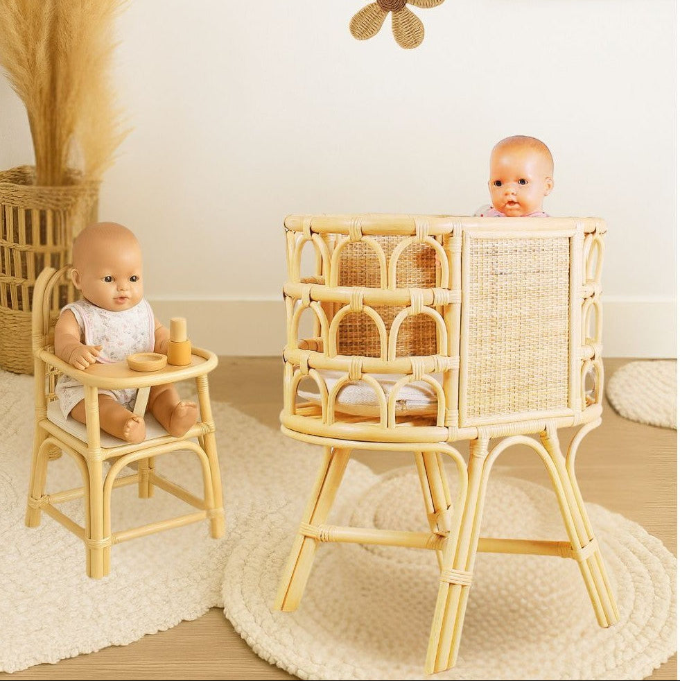 Two baby dolls in a rattan high chair and smaller stool with decorative flowers and a rabbit picture on the wall.