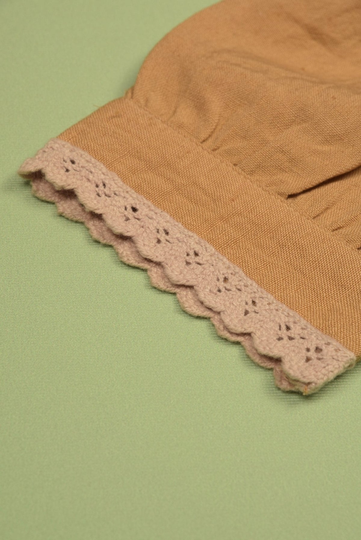 Close-up of the mustard puff sleeve with decorative scalloped trim.