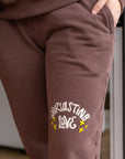 Brown sweatpants with 'Endless Love' text and stars on a blurred indoor background