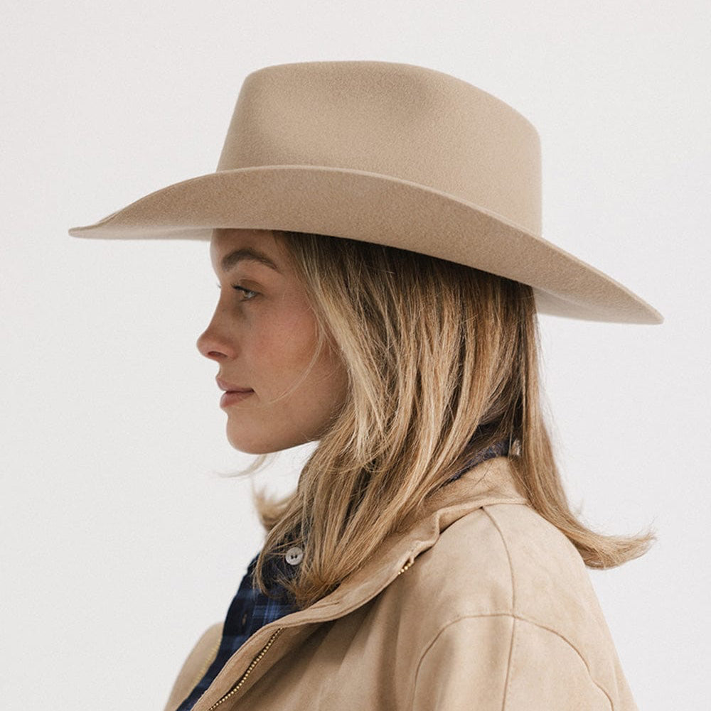 Woman wearing a beige hat and coat on a white background
