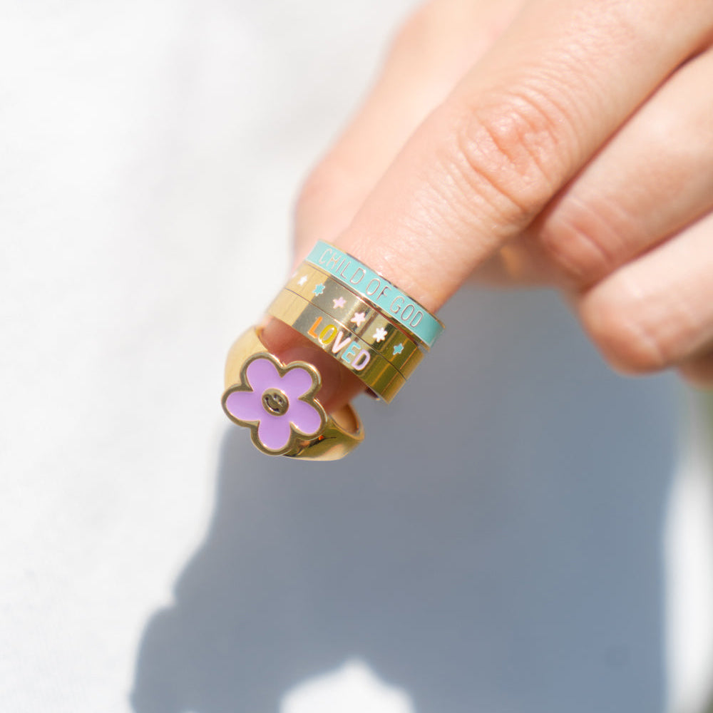Hand holding a small decorative item with a flower design on a white background