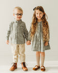 Boy in a green gingham shirt standing beside a girl wearing a coordinating gingham dress.