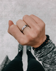 Silver-tone Highs and Lows Ring worn on a hand above a gray sleeve with dark bracelets