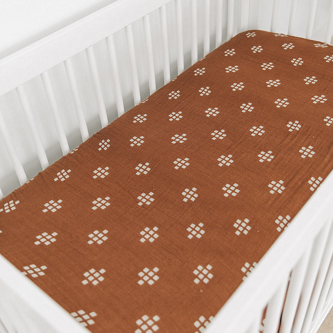 Brown crib sheet with white floral pattern on a white crib