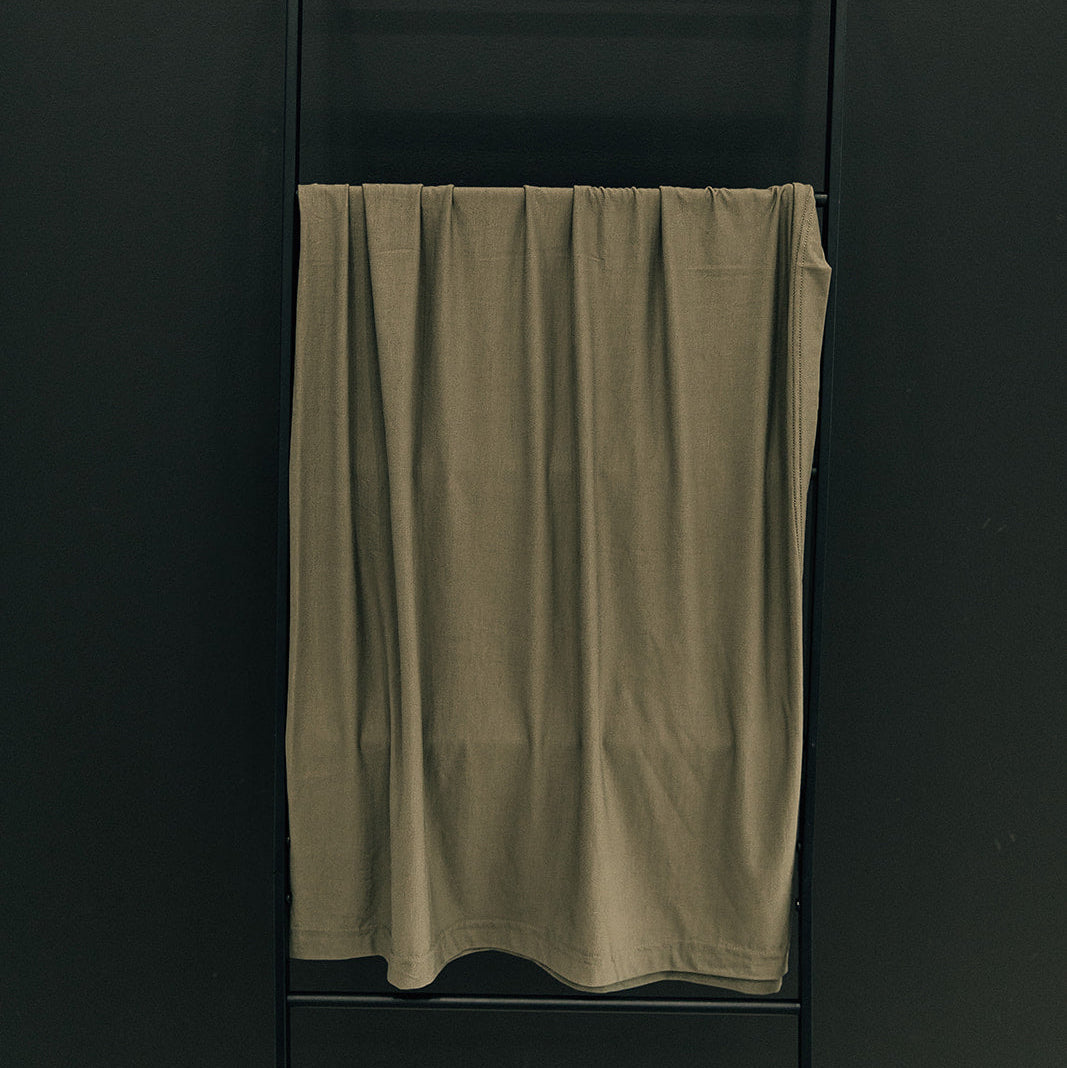 Green towel hanging on a black towel rack against a dark wall
