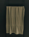 Green towel hanging on a black towel rack against a dark wall