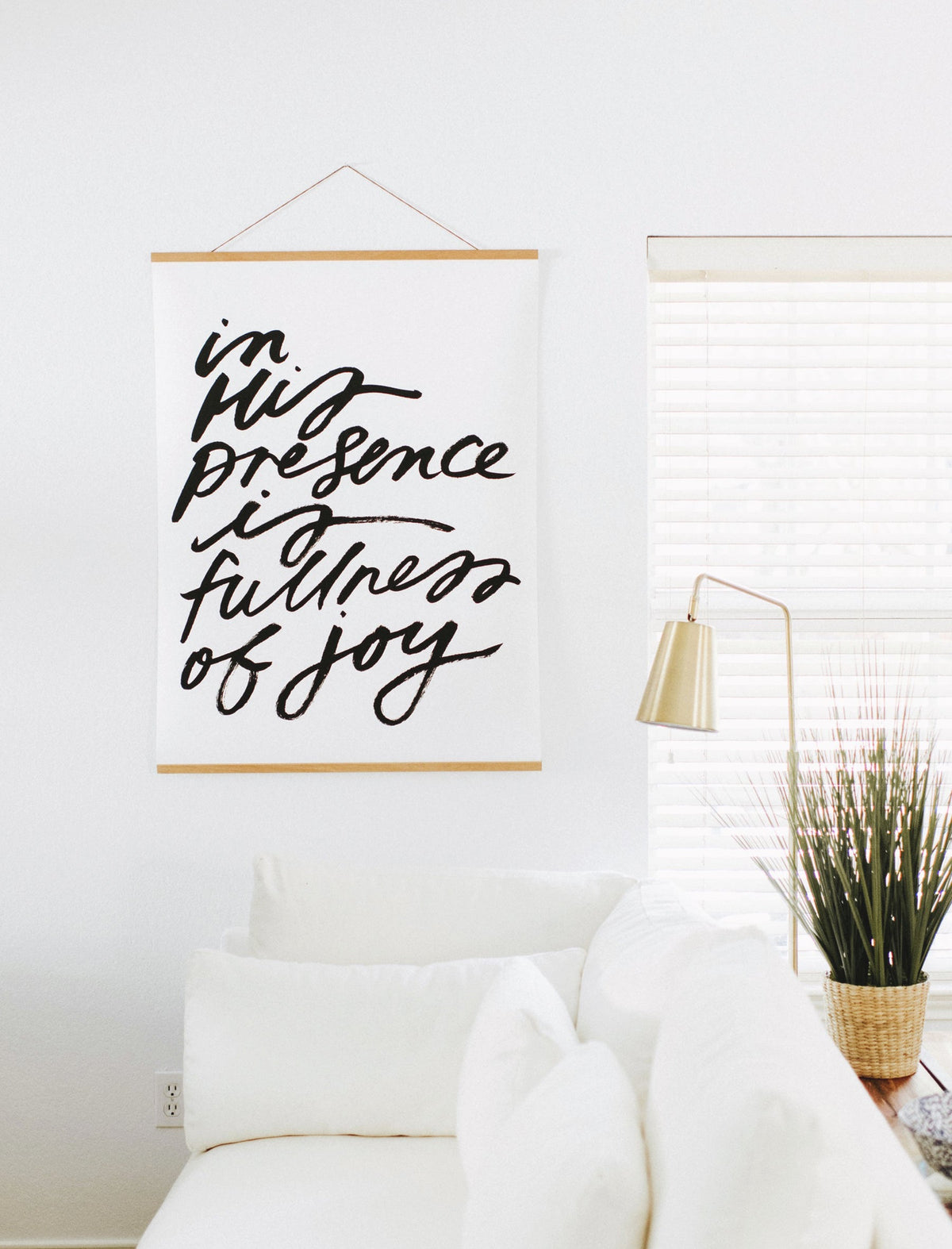 Black and white In His Presence Is Fullness of Joy wall art hanging above a white sofa.