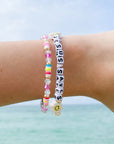 Two bracelets on a wrist with a clear blue sky background