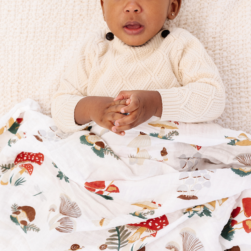 Child wrapped in a colorful blanket with a white knit blanket underneath