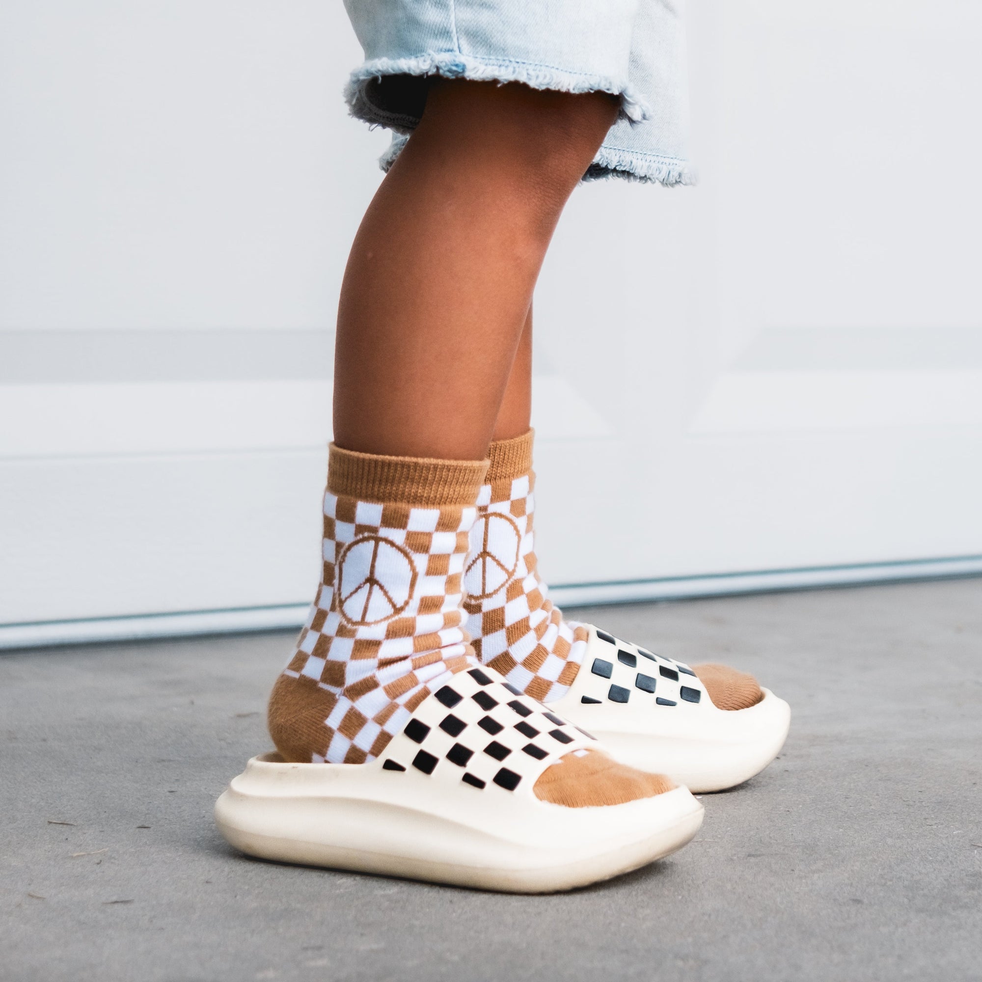 Person wearing checkered socks with a peace symbol design on a neutral background
