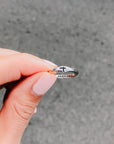 Hand holding a silver-tone cross promise ring to show its band and cross detail
