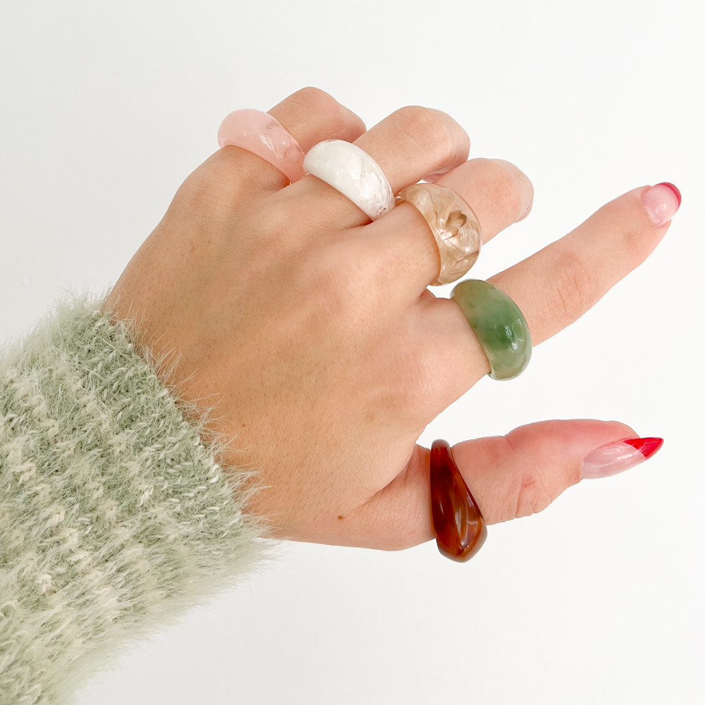 Hand wearing multiple rings on a white background