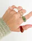 Hand wearing multiple rings on a white background