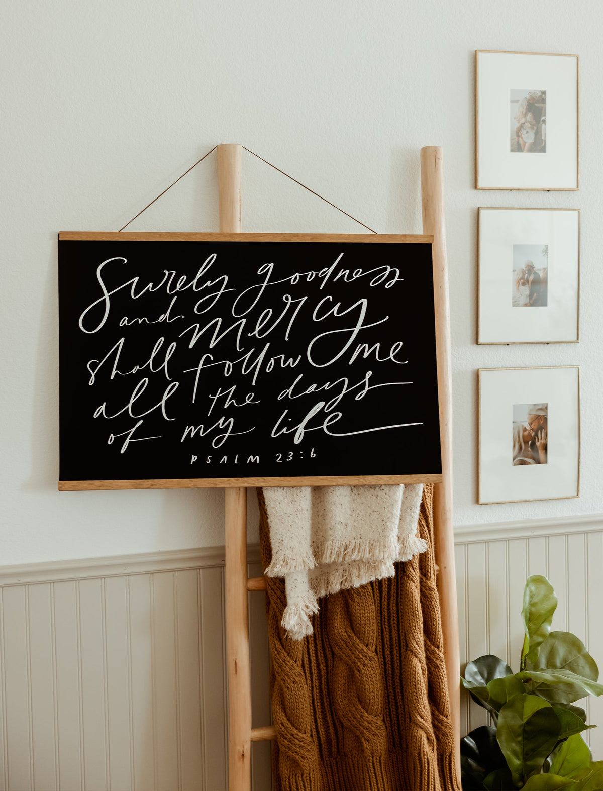 Surely Goodness Scripture wall art displayed with wooden hanging bars in a decorated home