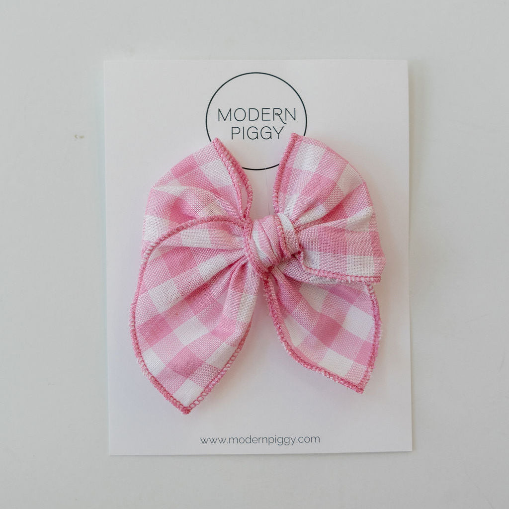 Pink checkered bow on a white card with 'Modern Piggy' branding.